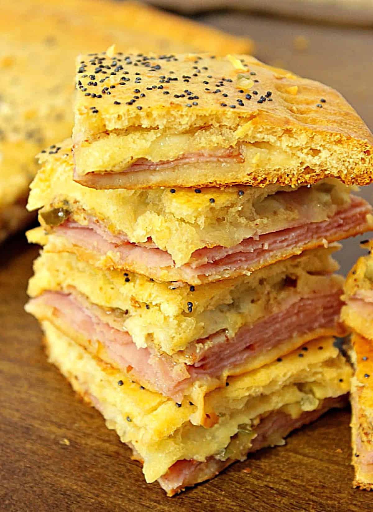 A stack of ham and cheese crescent appetizer squares with melted cheese in the middle.