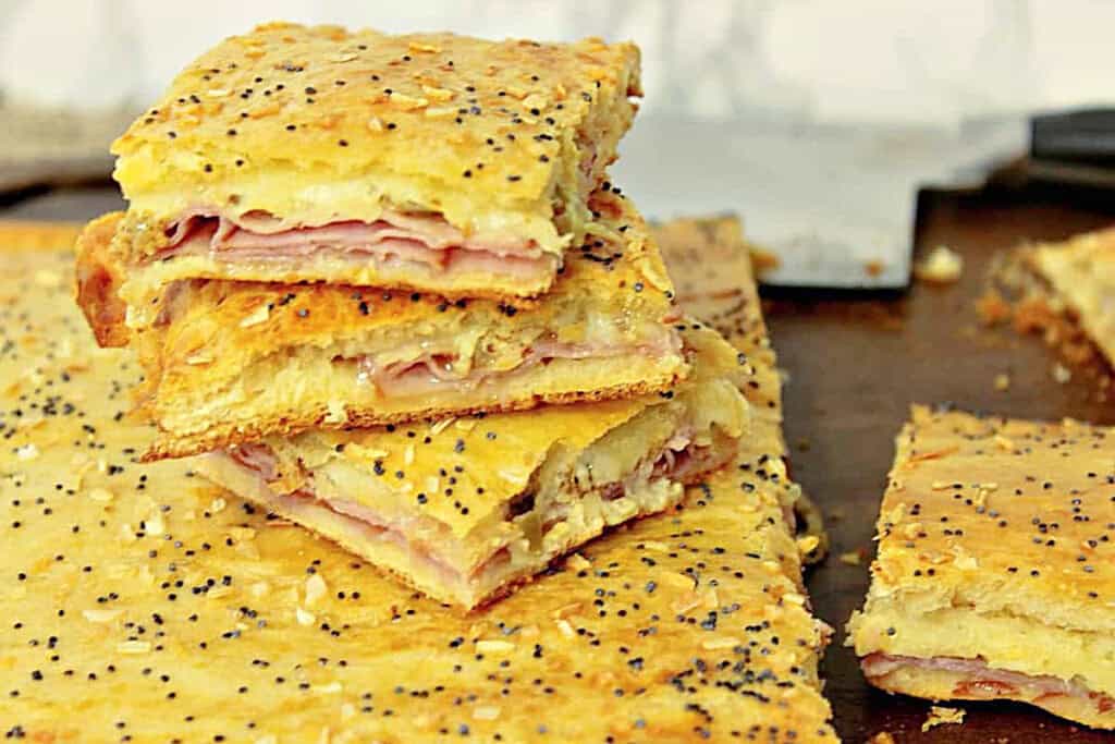 Poppy seed topped ham and cheese crescent appetizer squares cut for serving.