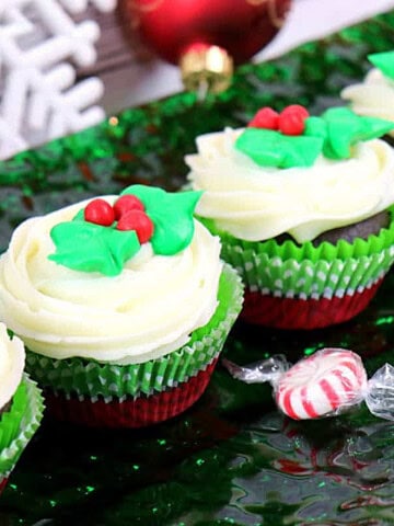 Delicious looking Peppermint Filled Chocolate Holly Berry Cupcakes with mounds of buttercream frosting and festive decoration.