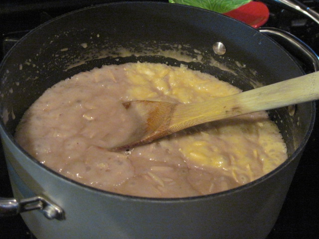 Bubbling almond toffee with a wooden spoon in a saucepan.