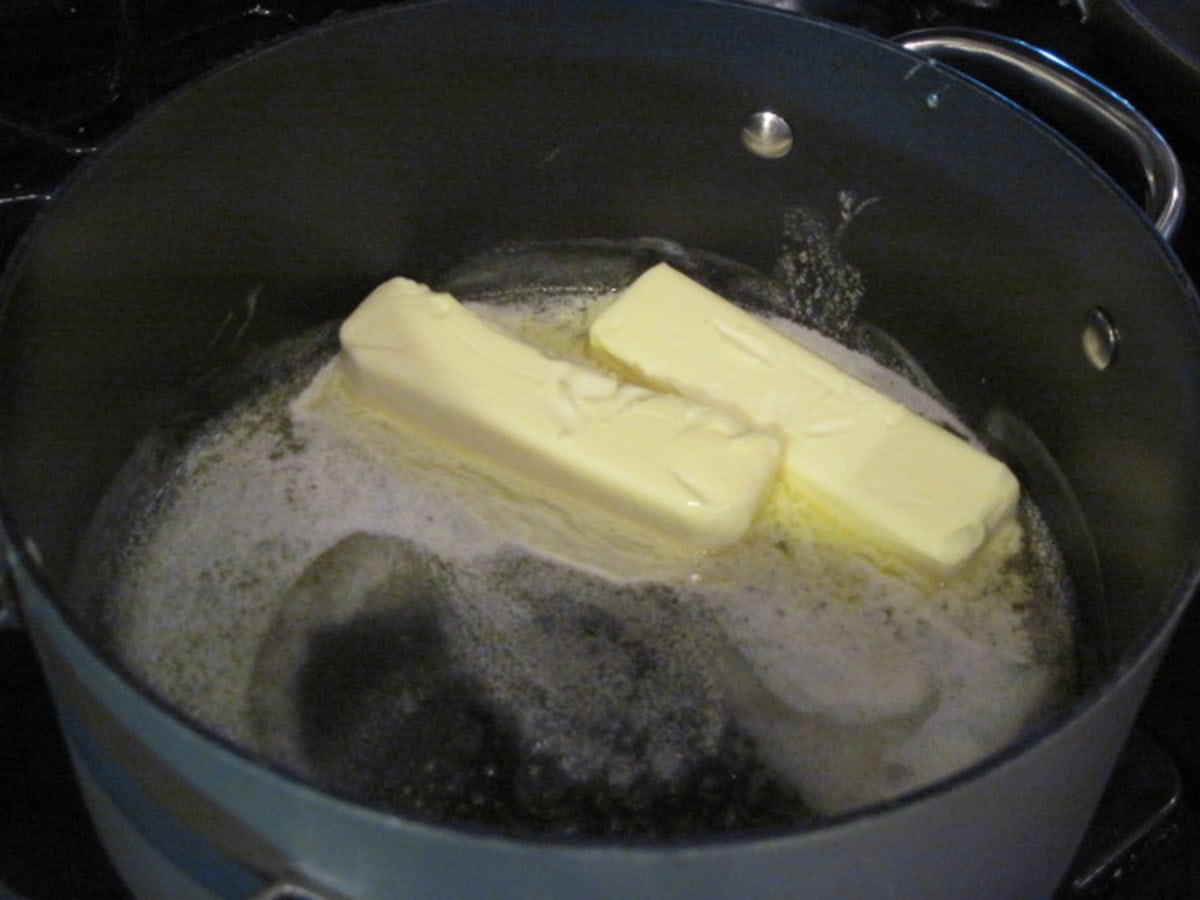 Two sticks of butter melting in a saucepan.