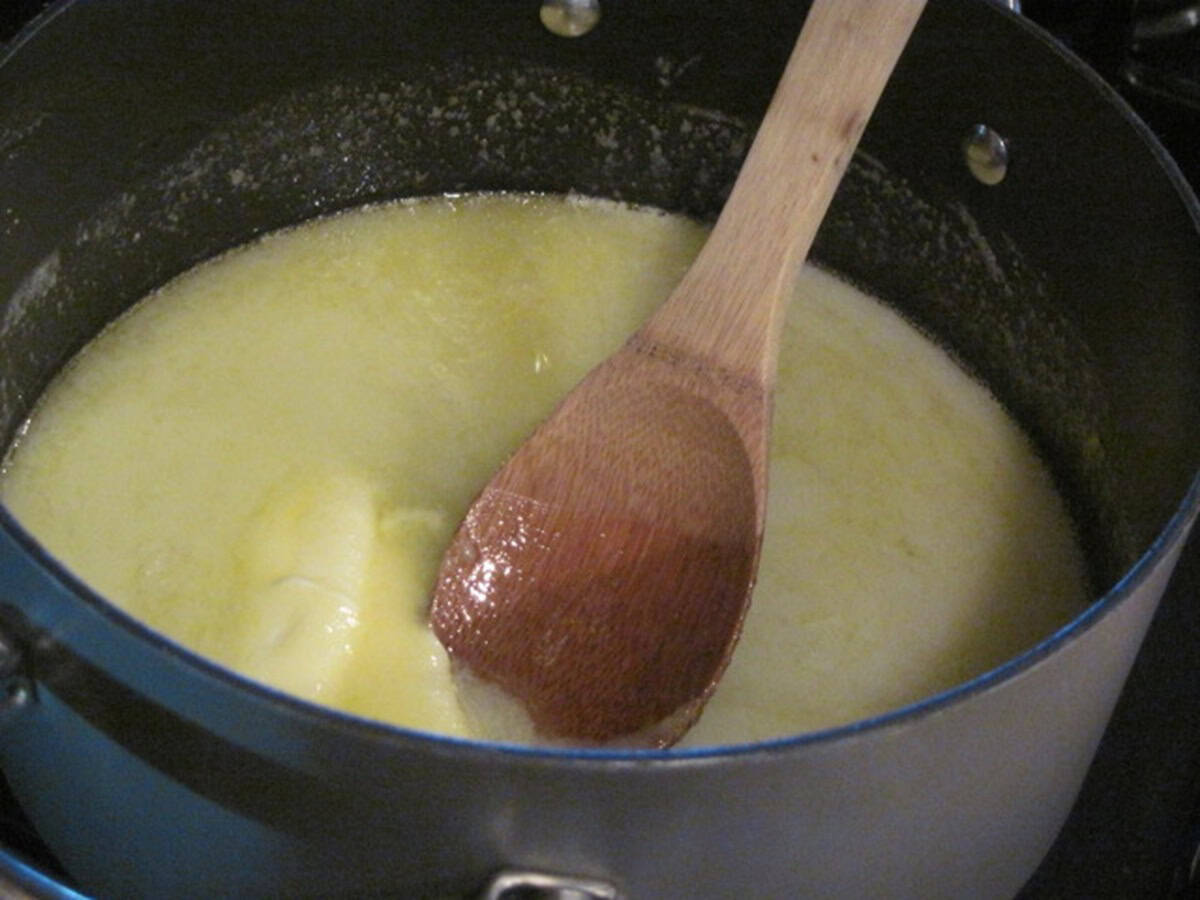 A wooden spoon in a saucepan with melted butter.