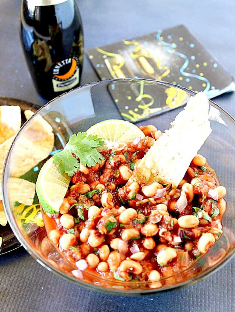 A glass bowl filled with black-eyed pea salsa and topped with fresh cilantro.