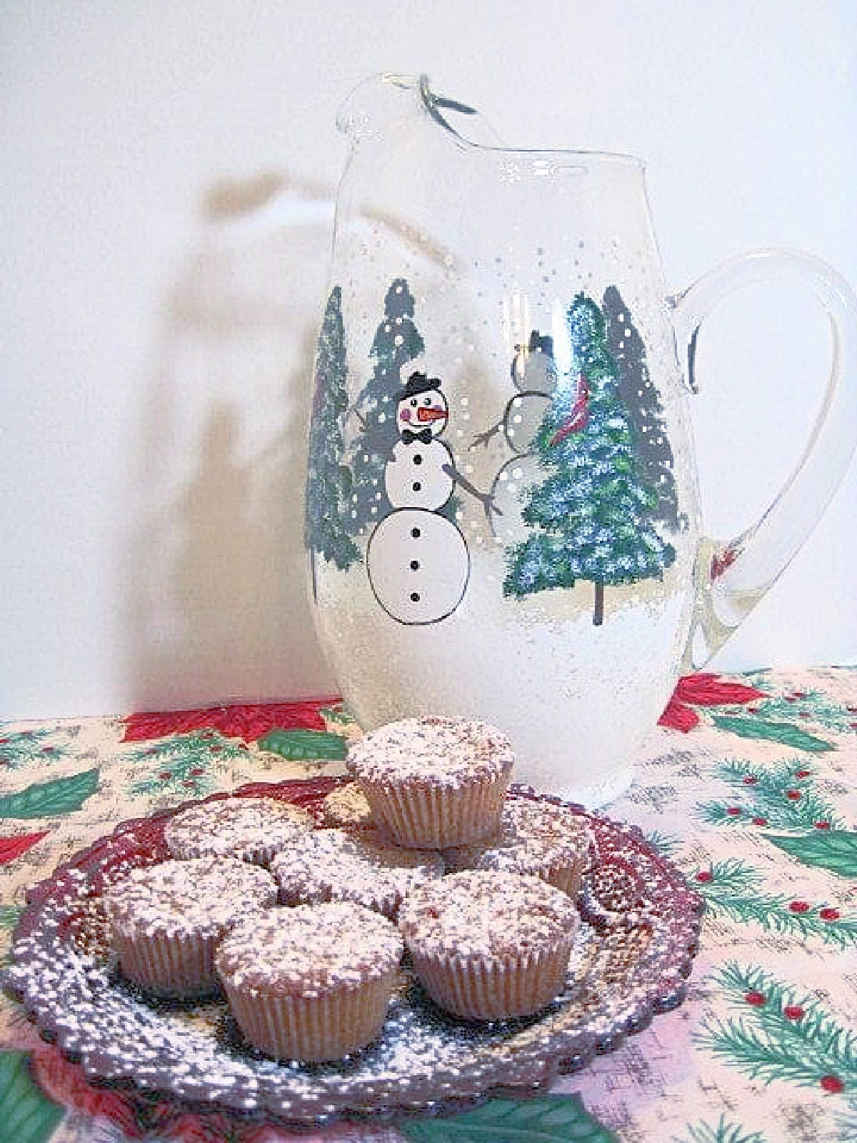 A small red glass plate filled with holiday nut cup cookies along with a dusting of confectioners sugar over top.