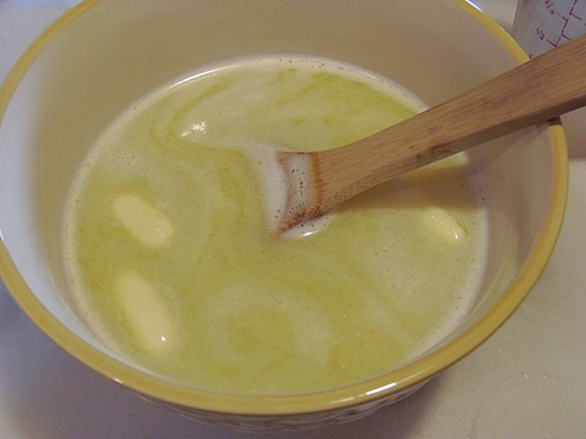 Melted butter and water in a bowl with a wooden spoon.