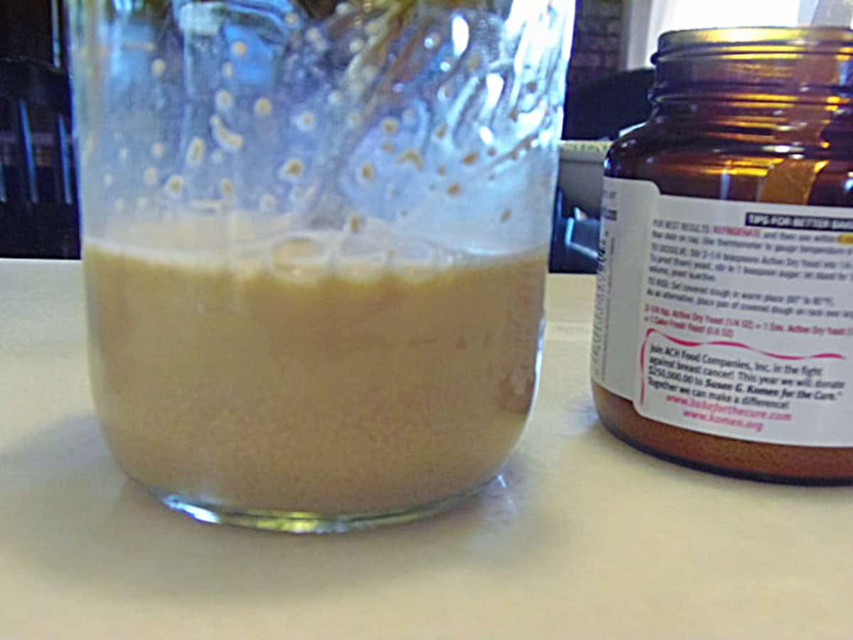 A mason jar with foamy yeast for making cinnamon rolls.