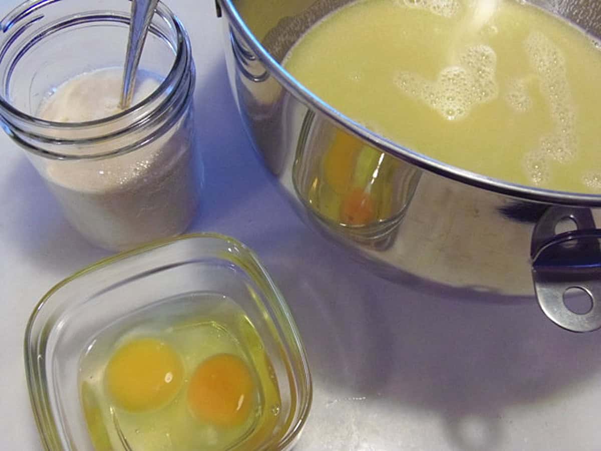 3 containers on the counter. One with eggs, one with yeast, and one with water and flour.