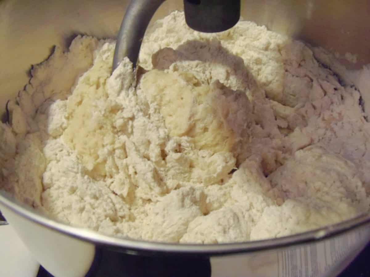 A stand mixer bowl making a cinnamon roll dough.