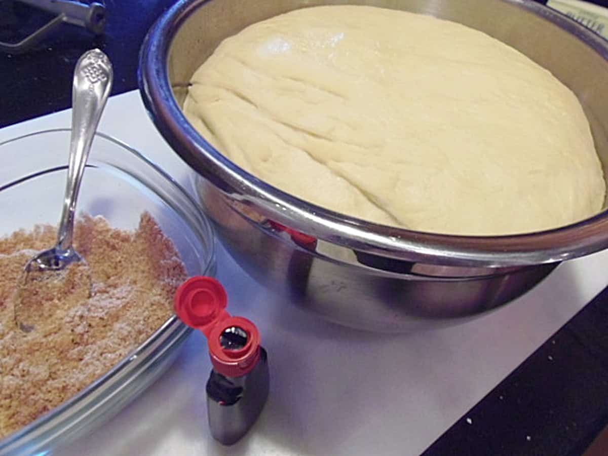 Two bowls on the counter. One with cinnamon sugar, and the other with cinnamon roll dough.