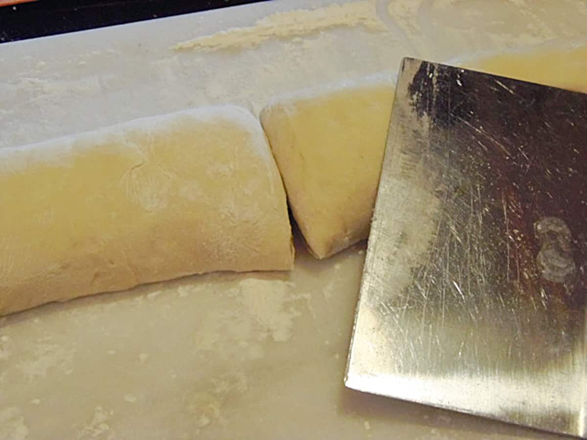 A log of rolled cinnamon roll dough after being cut in half.