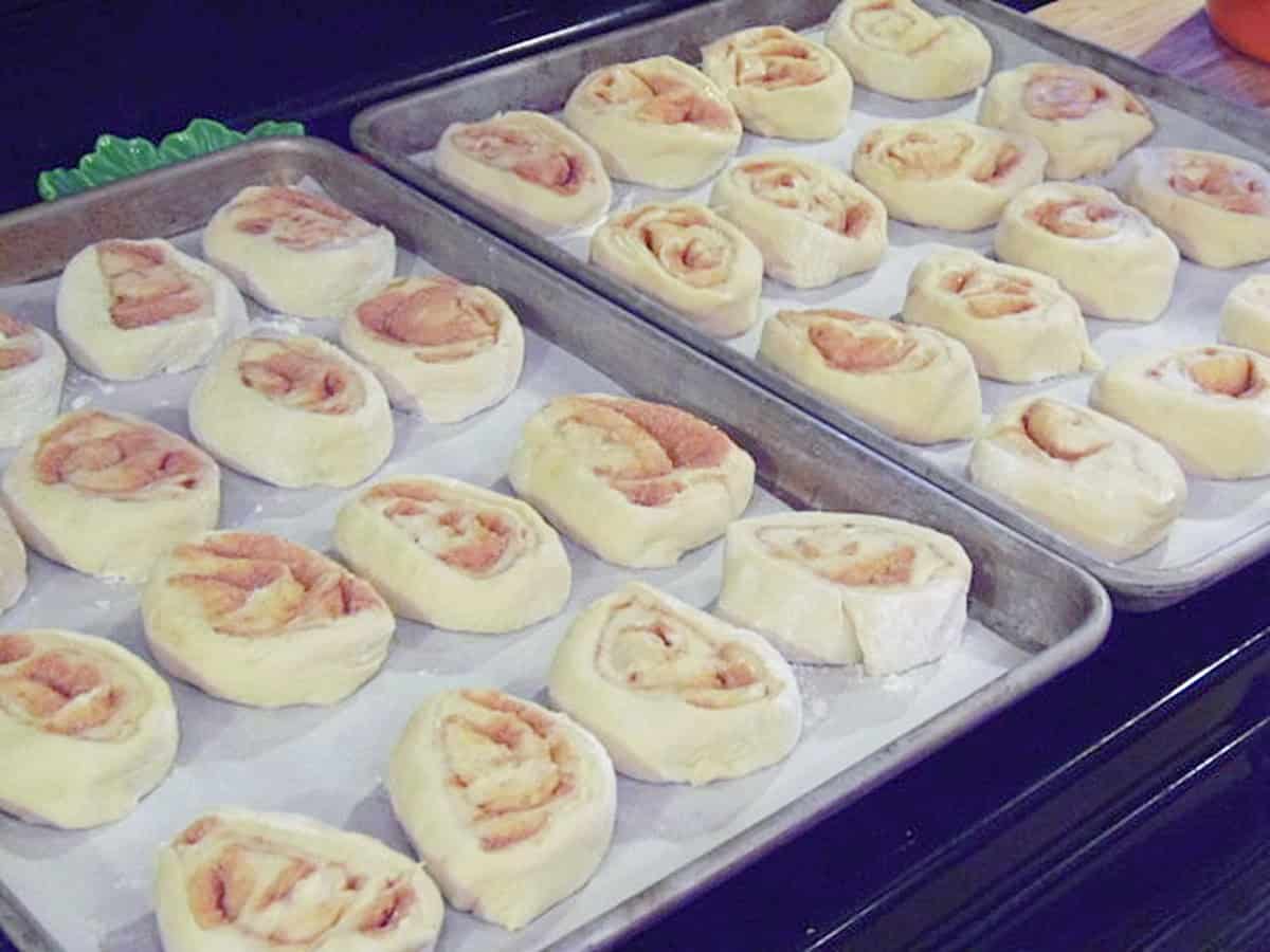 Two baking sheets filled with unproved cinnamon rolls.