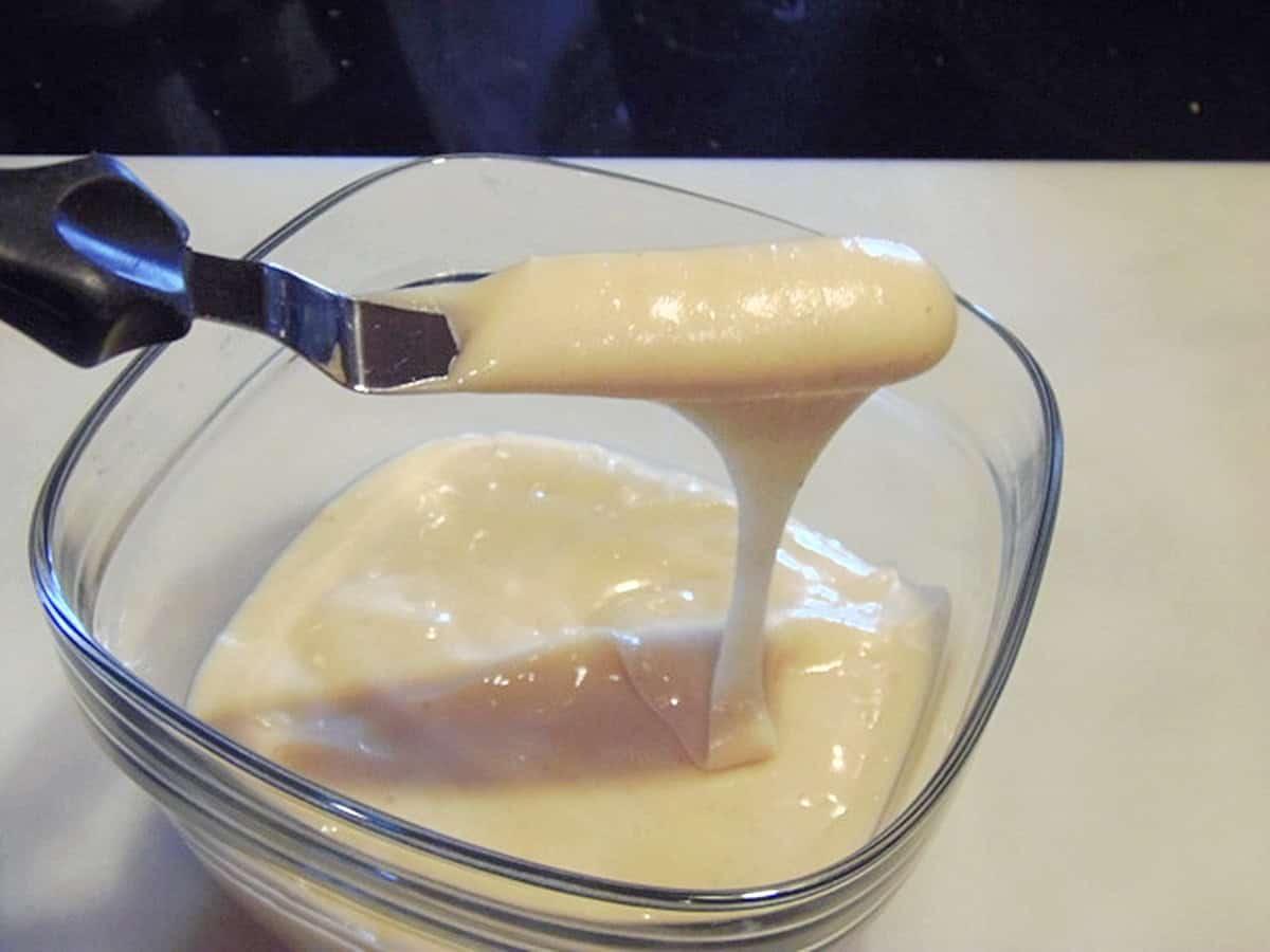 A dish of icing with an offset spatula showing the consistency.