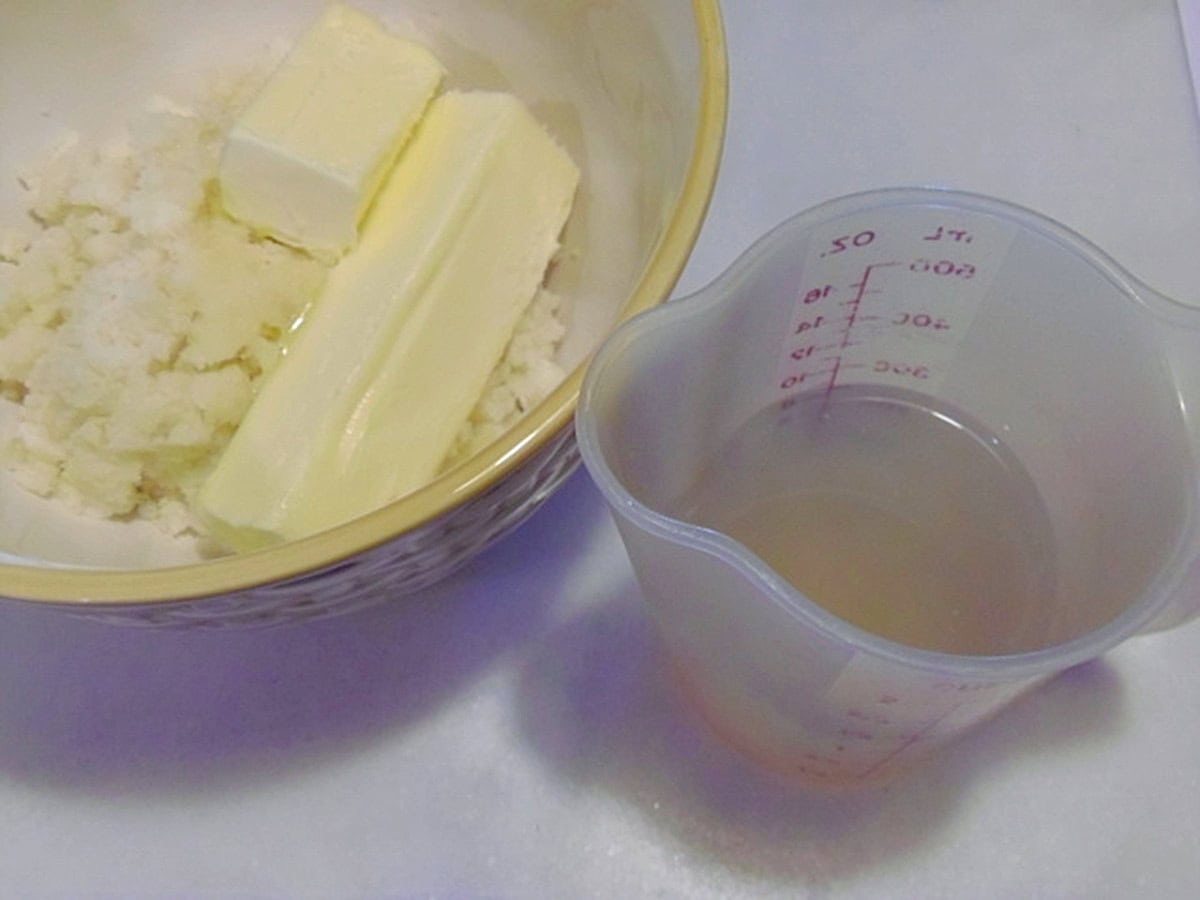 Mashed potatoes and stick butter in a bowl.
