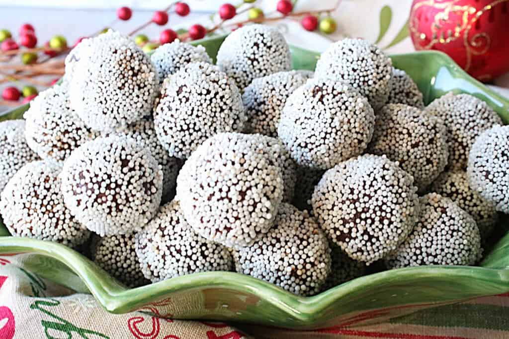 A festive holiday picture of chocolate peppermint truffles in a holiday bowl.