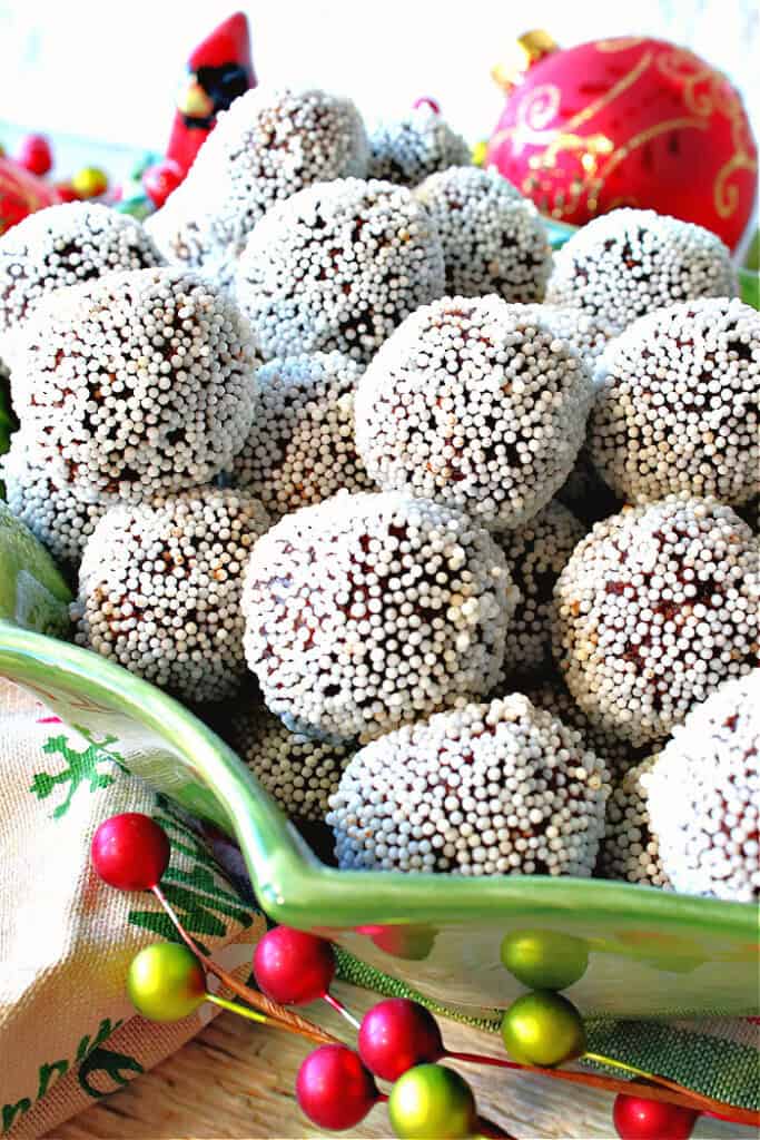 A green holly berry bowl filled with chocolate peppermint nonpareil truffles.