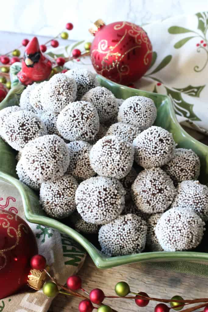 A holly berry and cardinal ceramic bowl filled with chocolate peppermint truffles for the holidays.