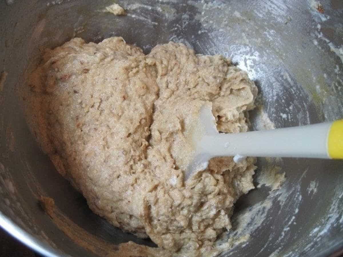 Holiday nut cup cookie batter in a silver bowl with a white spatula.