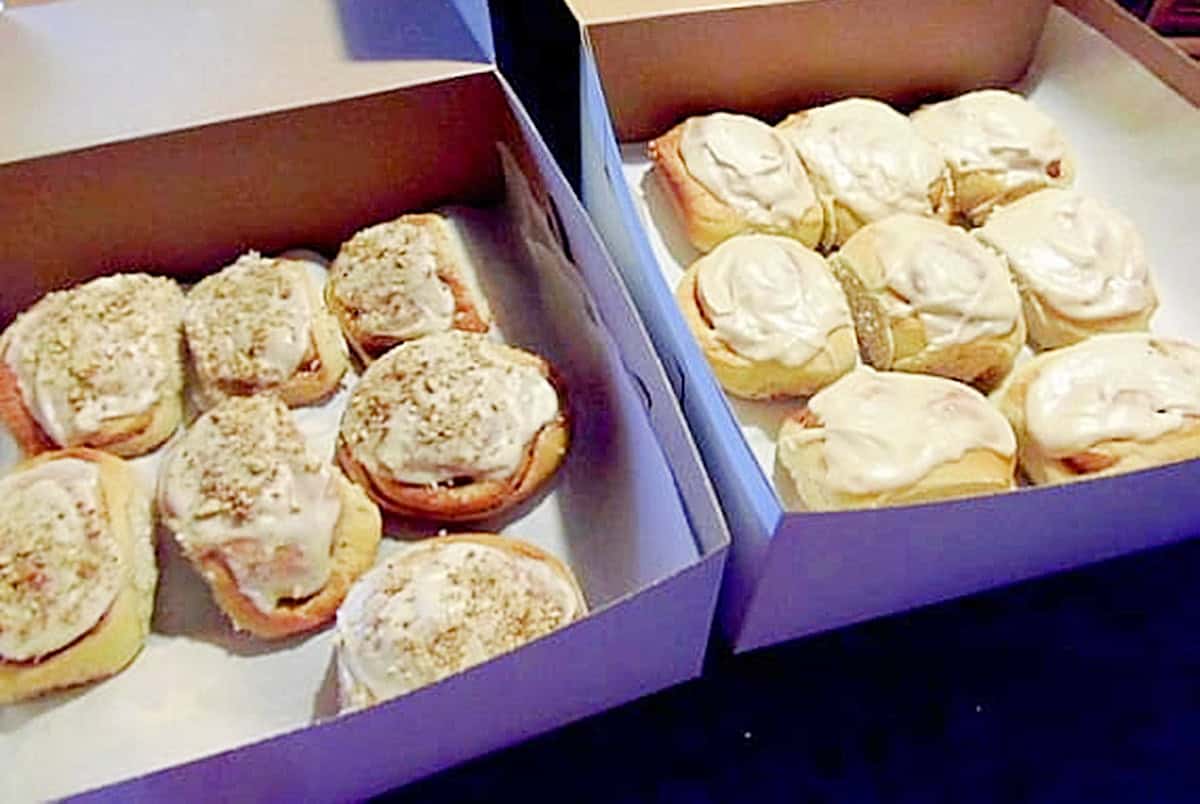 Two bakery boxes filled with homemade cinnamon rolls.
