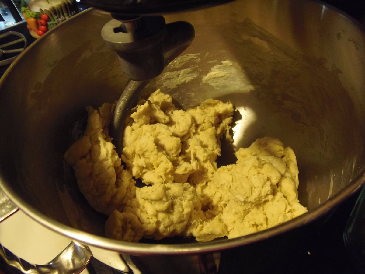 A shaggy bread dough in a stand mixer bowl.