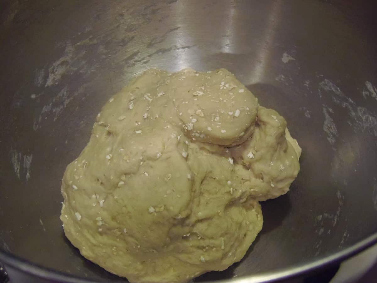 A sweet roll dough with oatmeal flecks in a silver bowl.