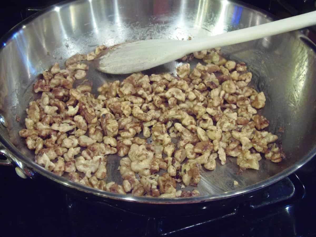 A bunch of chopped walnuts in a silver skillet for toasting.
