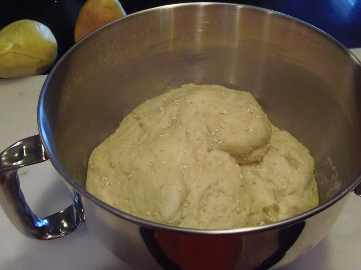 A proved sticky bun dough in a silver bowl.