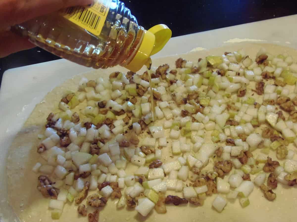 Honey bring drizzled over the filling of pears and walnuts making sticky buns.