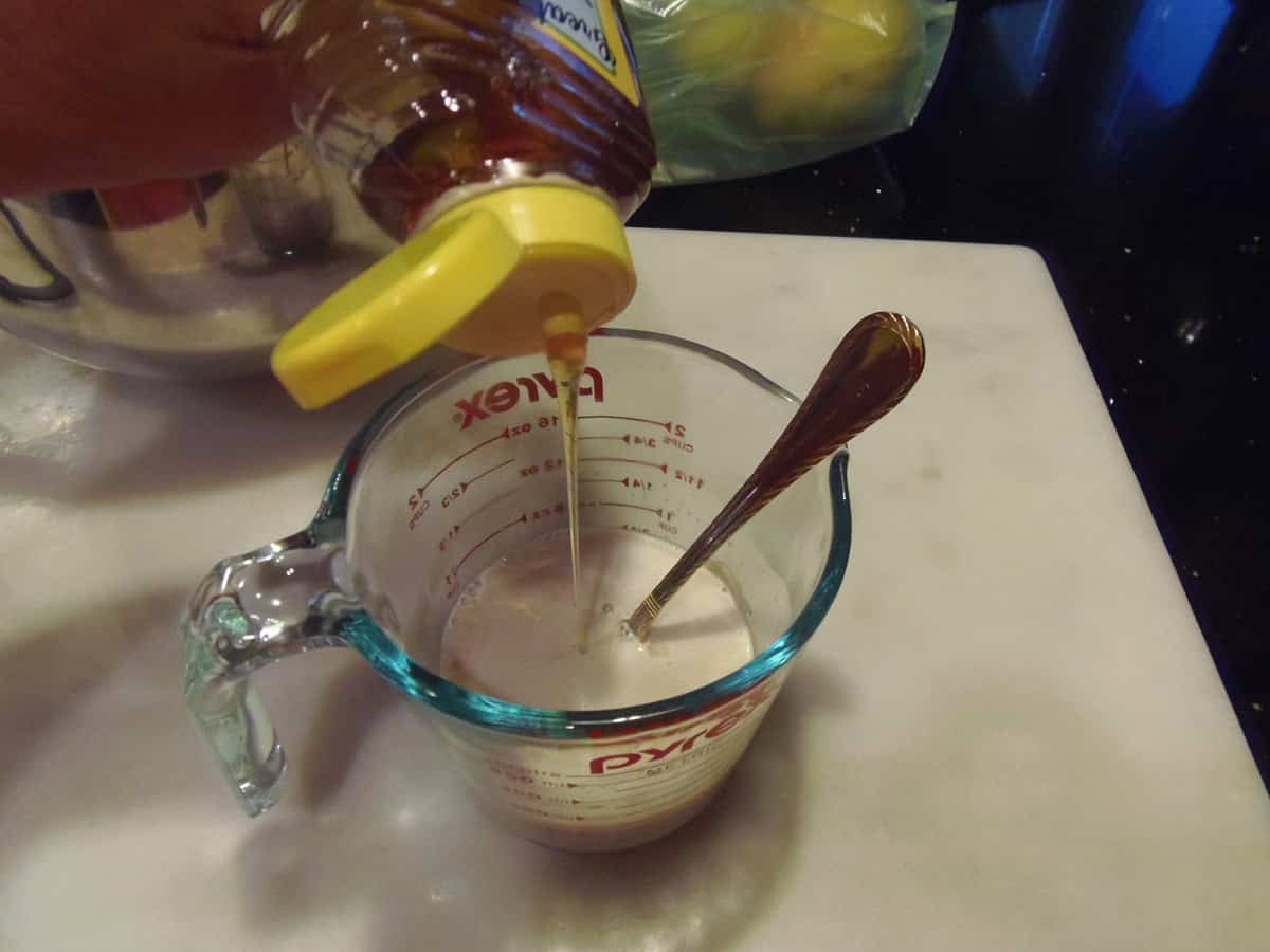 Honey being drizzled into a warm water and yeast mixture.