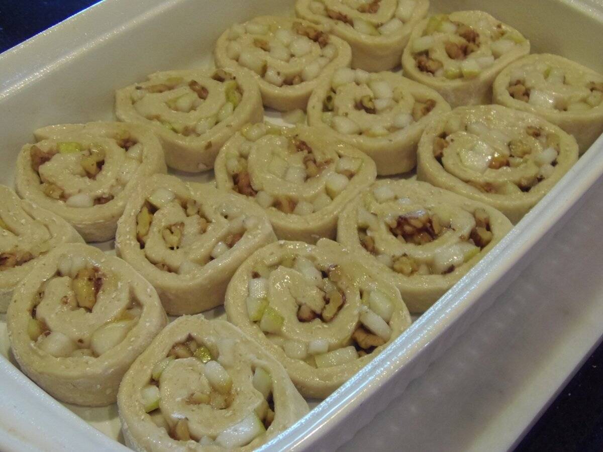 A filled baking dish of pear and walnut sticky buns before baking.