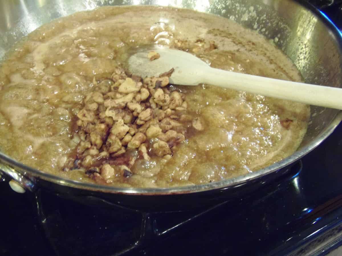A silver skillet with brown sugar and walnuts for making caramel.