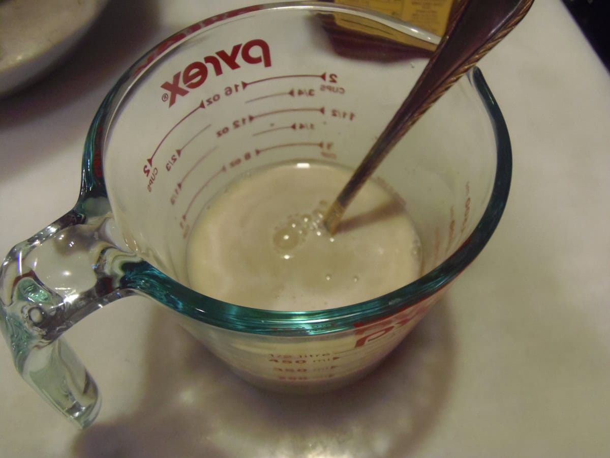 Yeast being dissolved in a measuring cup of warm water.