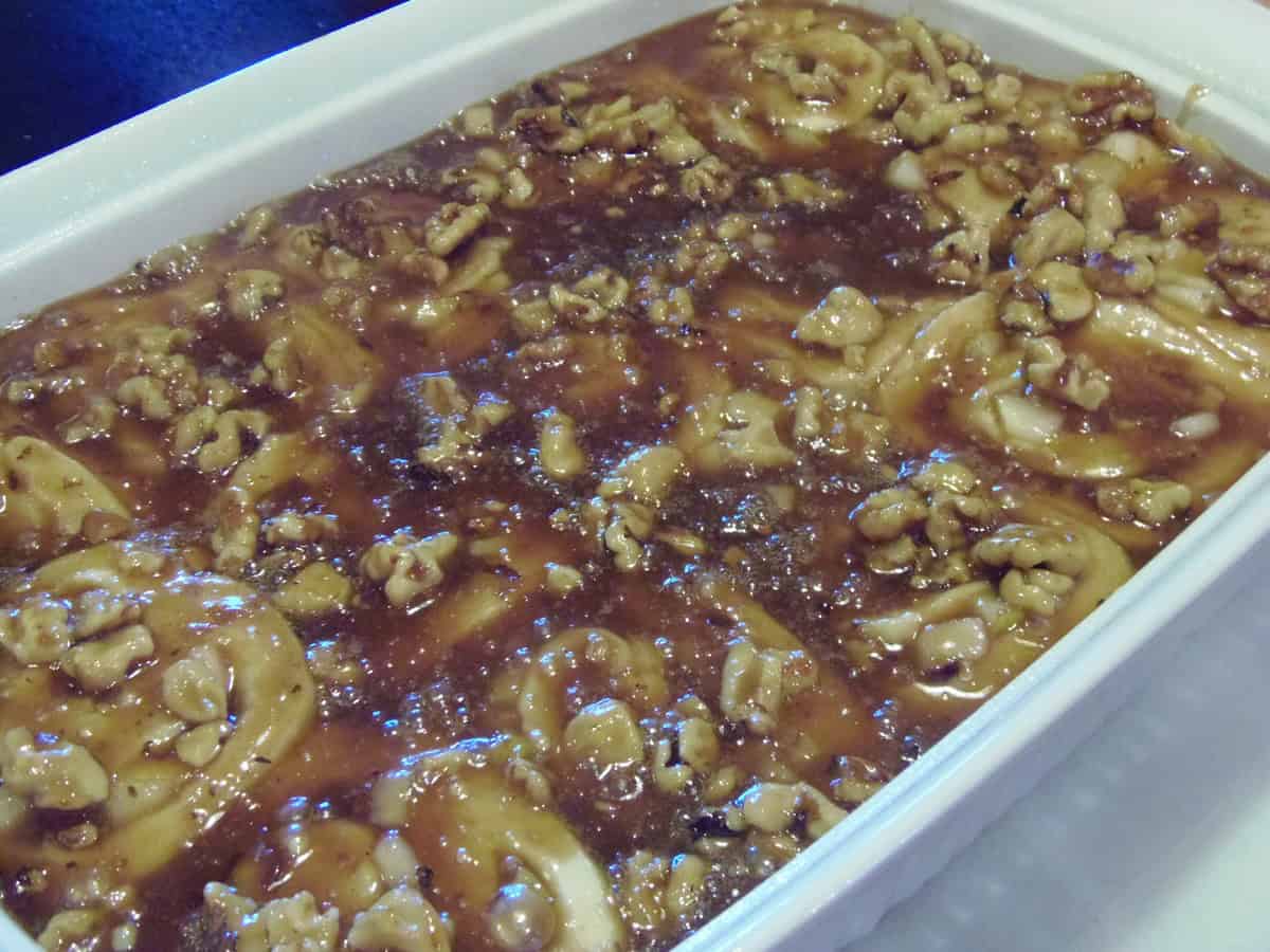 A white baking dish filled with gooey looking pear and walnut sticky buns just out of the oven.