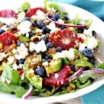 A bright, colorful salad made with blood orange slices, avocados, blueberries, lettuce and feta cheese.