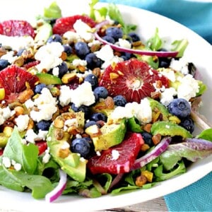 A bright, colorful salad made with blood orange slices, avocados, blueberries, lettuce and feta cheese.