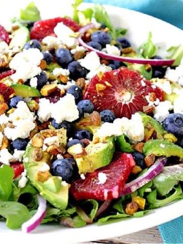A bright, colorful salad made with blood orange slices, avocados, blueberries, lettuce and feta cheese.