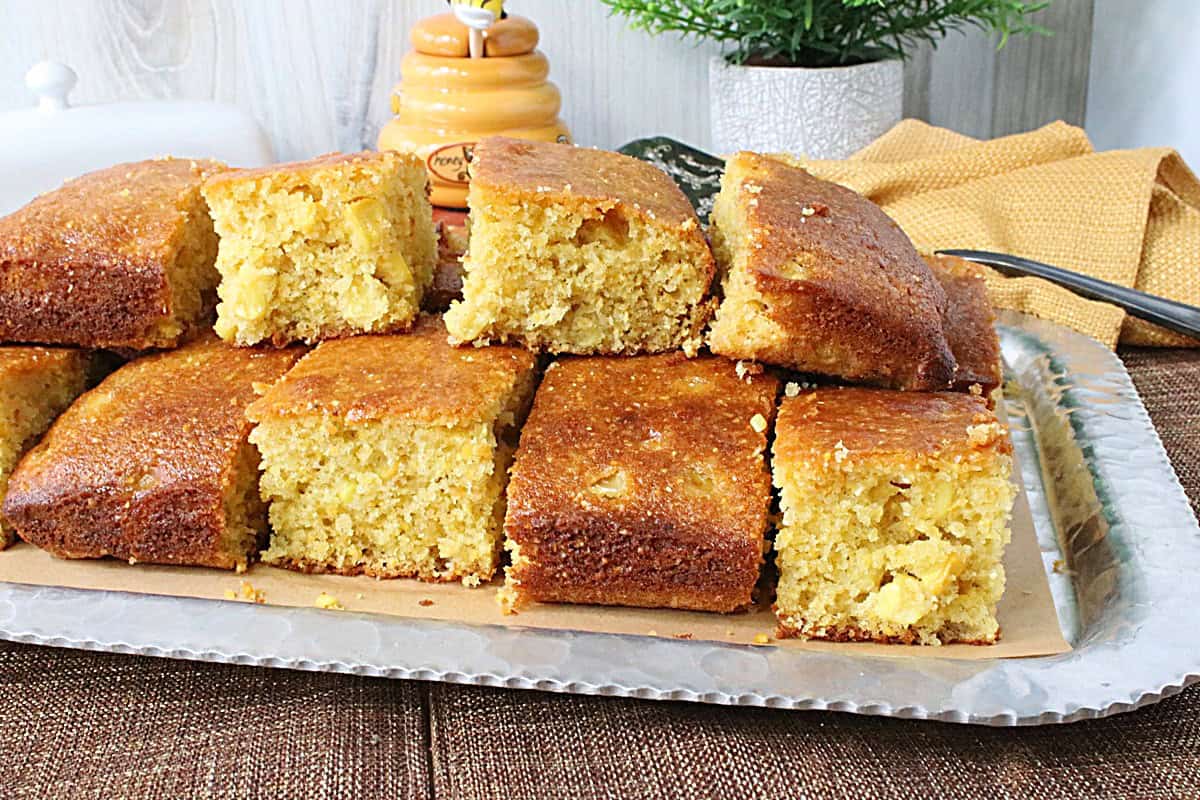 A silver tray loaded with golden squares of stacked cornbread.