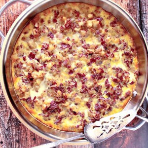 A Corned Beef Hash Frittata in a silver skillet with a silver serving spatula on top.