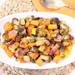 Fall colored roasted produce in an oval white bowl.