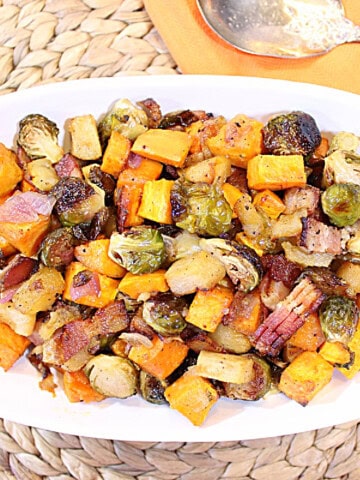 Fall colored roasted produce in an oval white bowl.