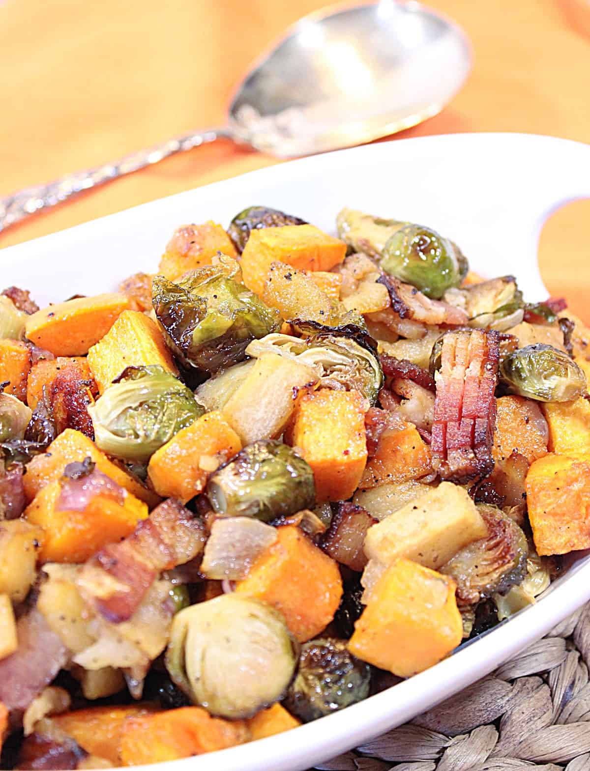 Fall's bounty of flavors and colors shine brightly in this dish of Sweet Savory Roasted Sweet Potatoes Brussels Sprouts with Apples. - Kudos Kitchen by Renee - kudoskitchenbyrenee.com Roasted fall vegetables with brown caramelization all piled into a white bowl ready for serving.