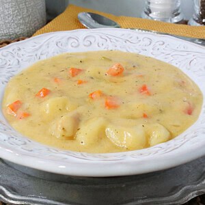 Plump potato gnocchi in a bowl of cheddar soup with carrots, celery and bacon.