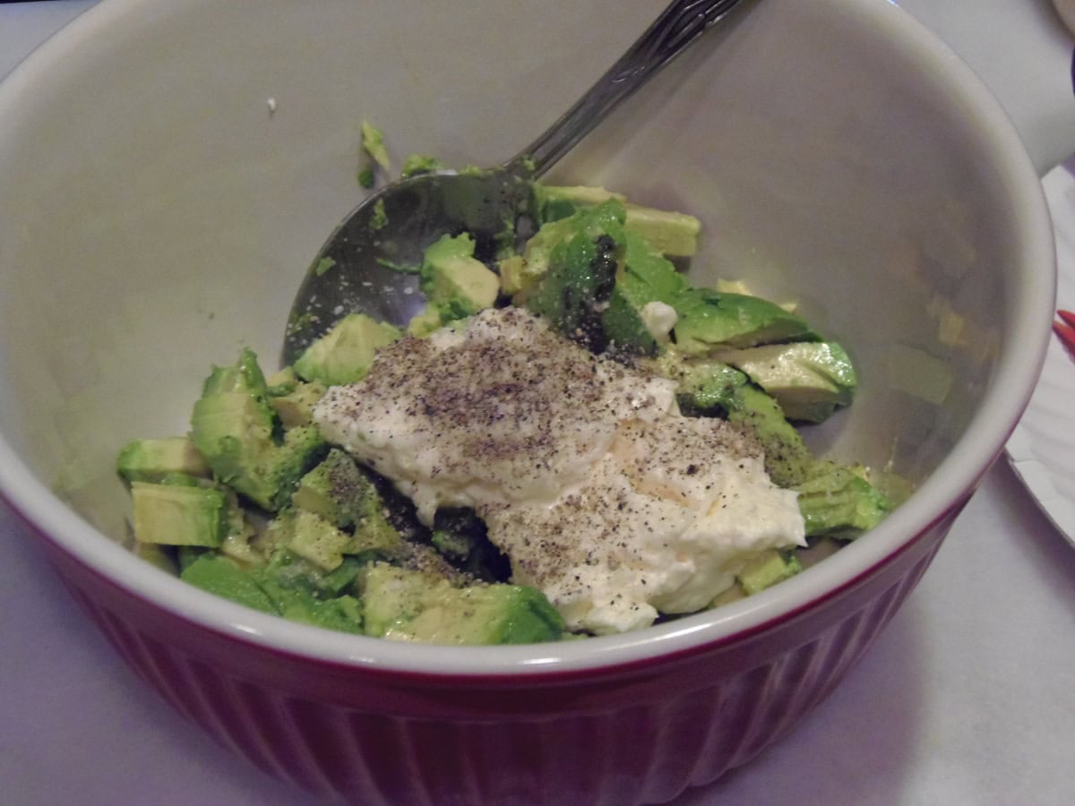 A bowl of diced avocado, mayonnaise, salt and pepper in a bowl.