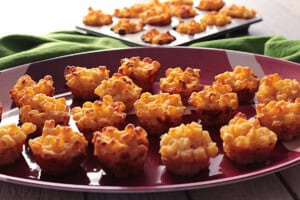 A bunch of macaroni and cheese appetizer cups on a football platter.