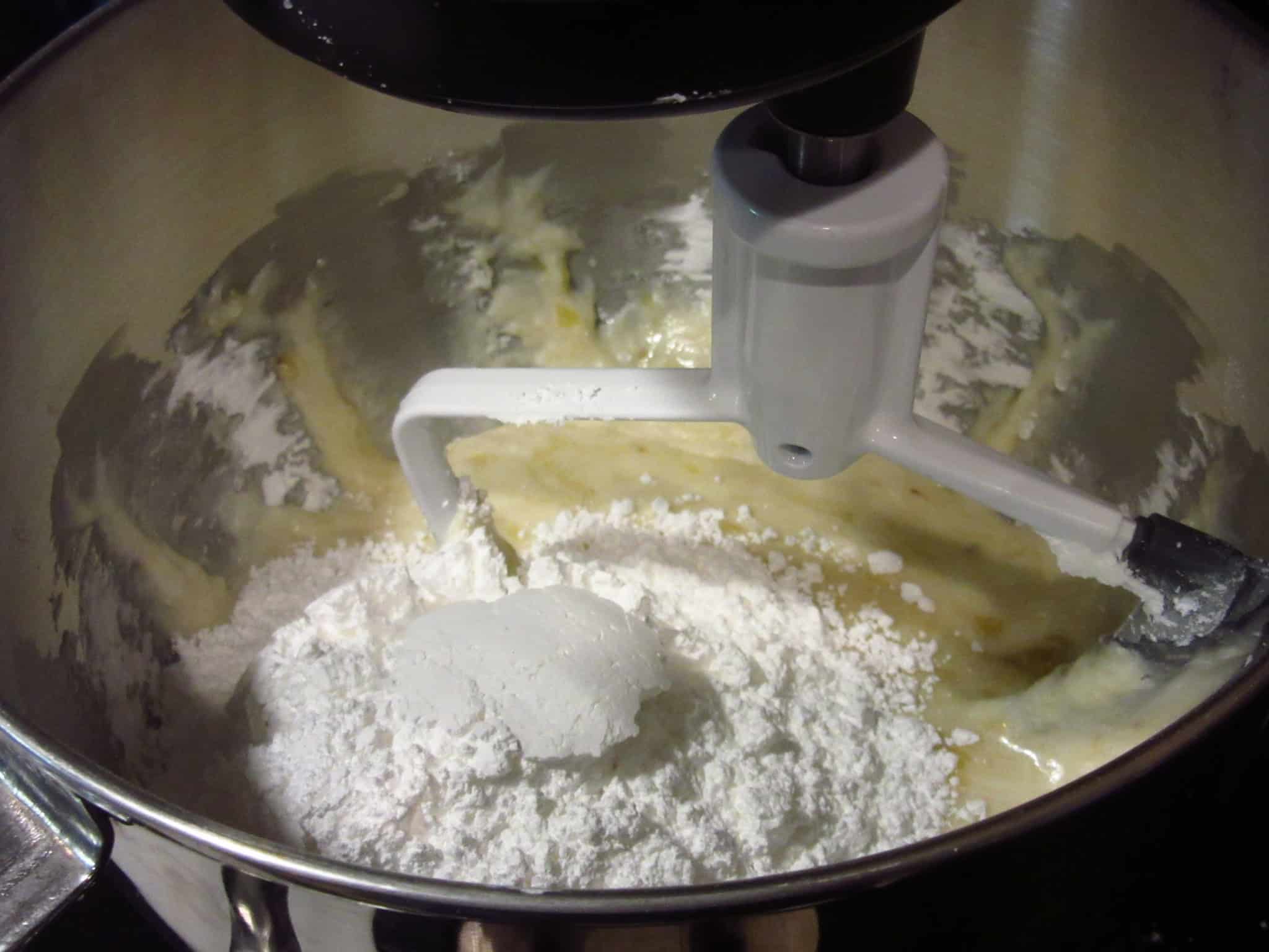 Confectioners sugar and mashed bananas in a stand mixer bowl.