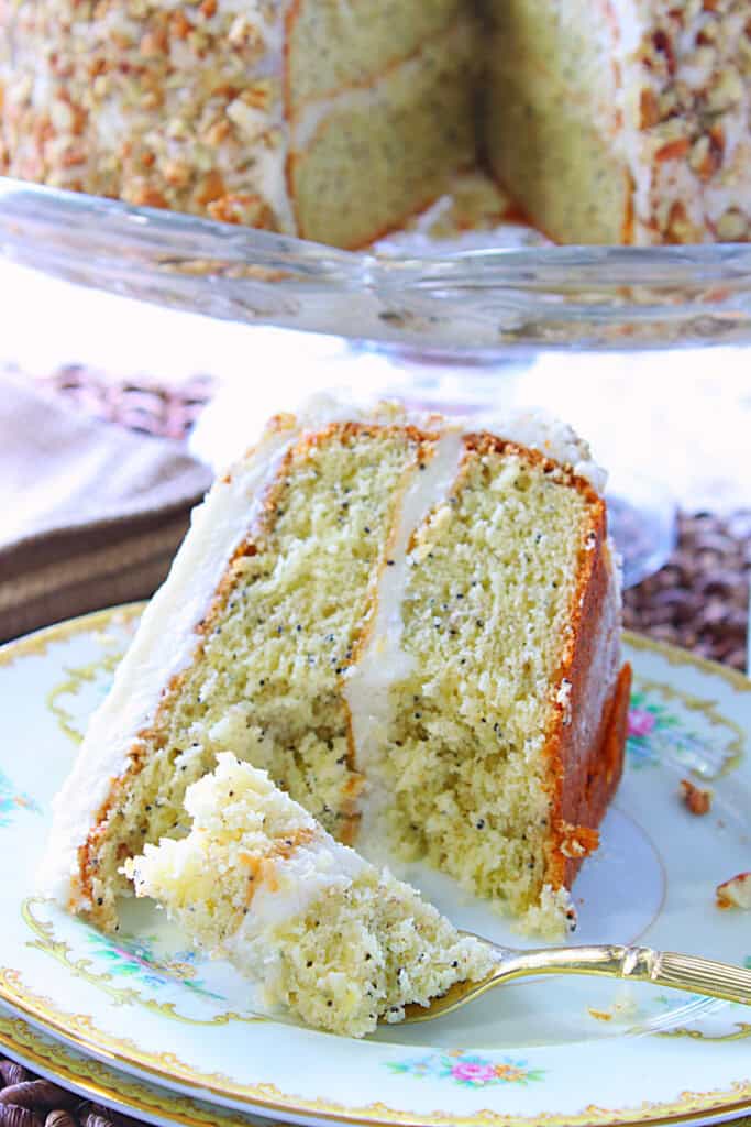 A slice of banana poppy seed cake with a fork and a bite-sized portion on a pretty plate.