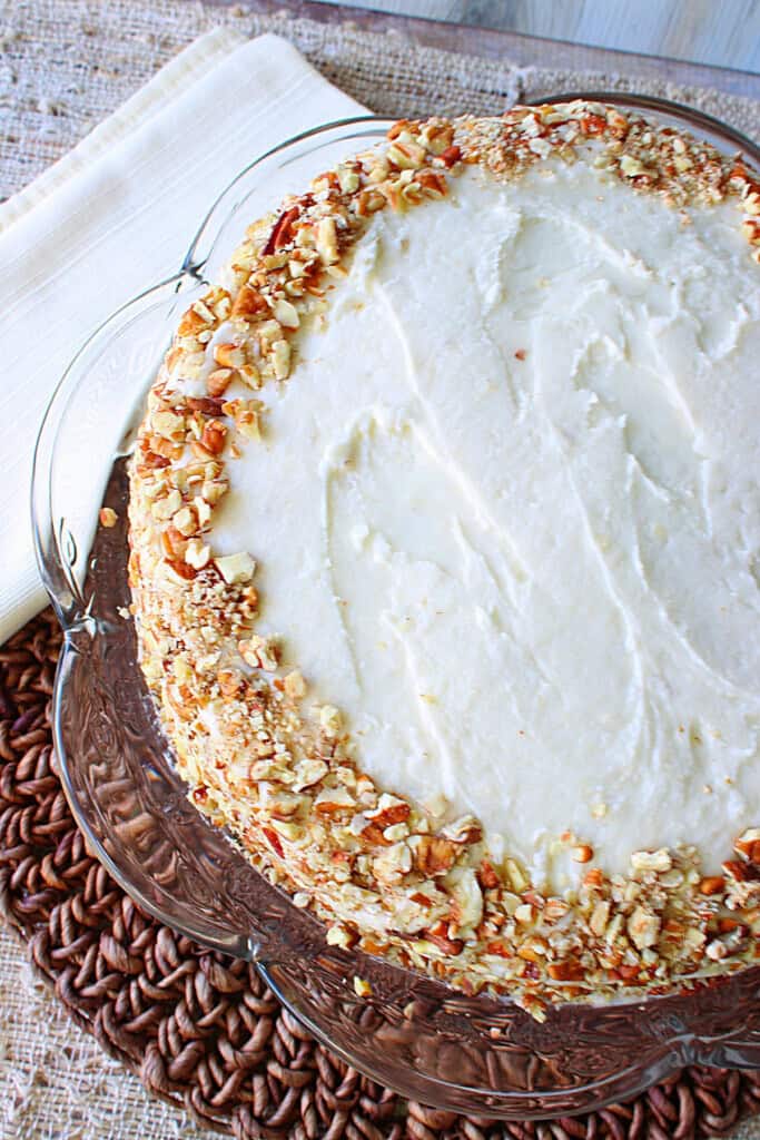 A Banana Poppy Seed Cake with frosting covered with chopped pecans around the side.