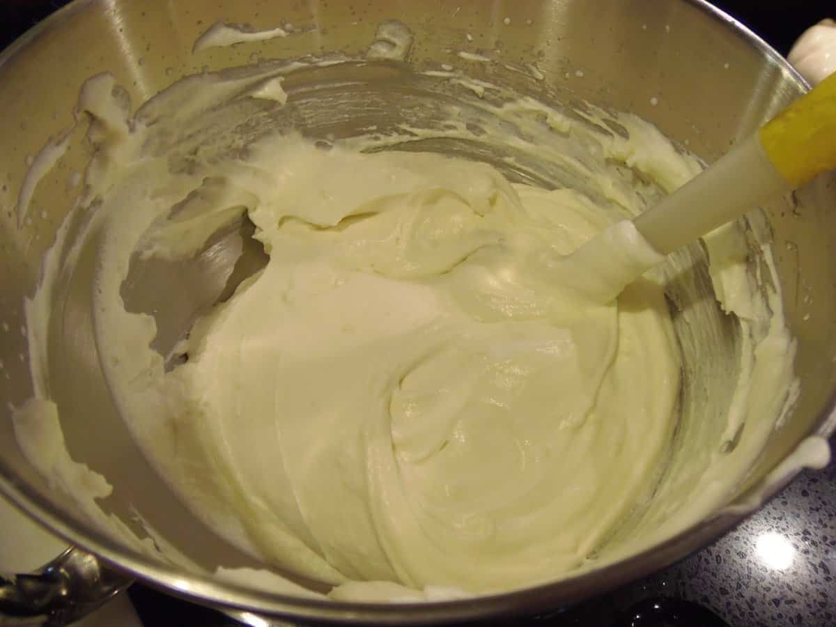 A mixing bowl with creamy lemon curd whipped cream and a spatula.