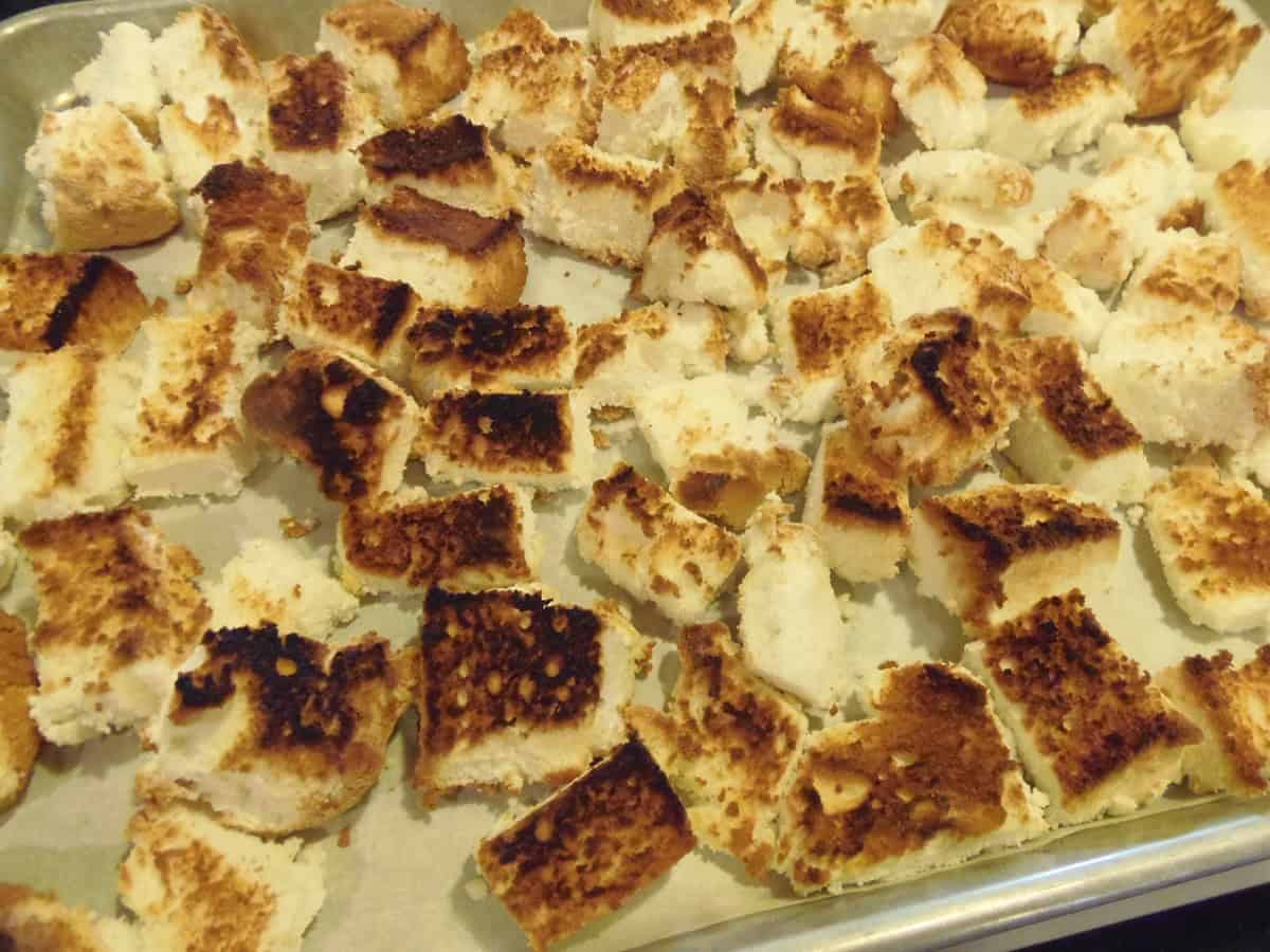 Cubes of golden angel food cake on a rimmed baking sheet before making a trifle.