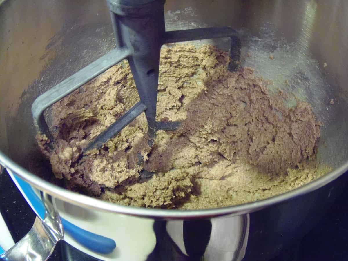 A thick muffin dough in a stand mixer bowl with the paddle attachment.