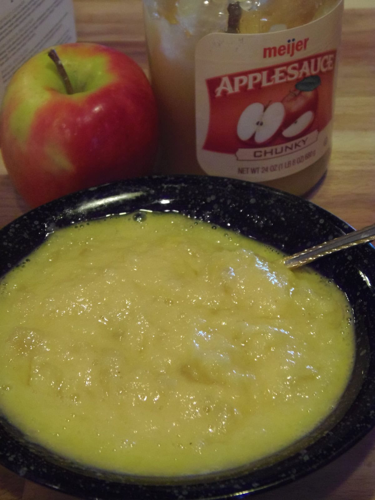 Applesauce in a black bowl with a spoon.